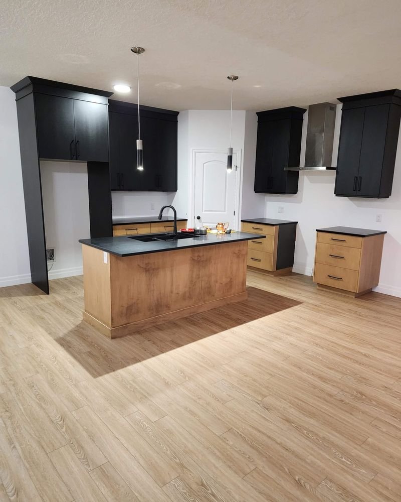 Open concept kitchen with a custom wood island, black cabinetry and LVP flooring, renovated by Elm Kitchen in Elgin County