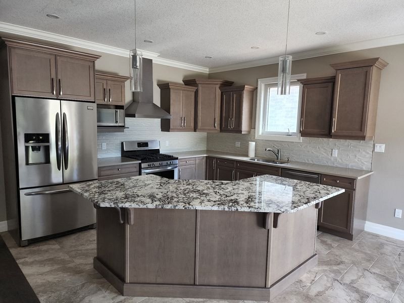 Kitchen with stained shaker cabinets, crown moulding and a granite-topped island, renovated by Elm Kitchen