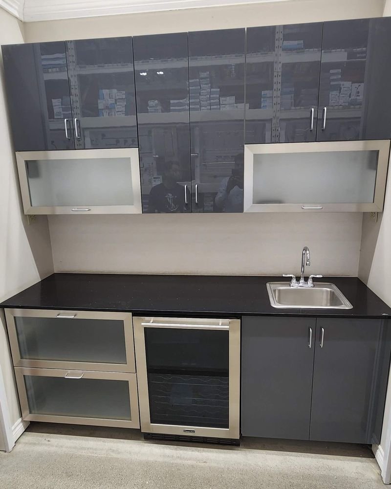 Custom wet bar with grey cabinetry, a beverage fridge and black quartz counters, built by Elm Kitchen in St. Thomas