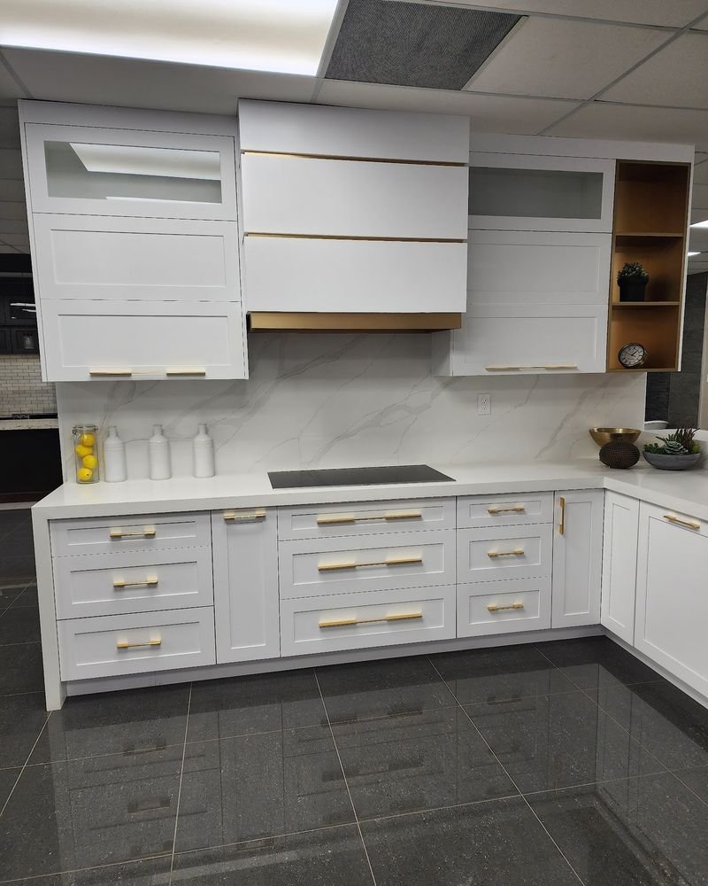 White kitchen with brass handles, a quartz backsplash and a slab range hood, renovated by Elm Kitchen