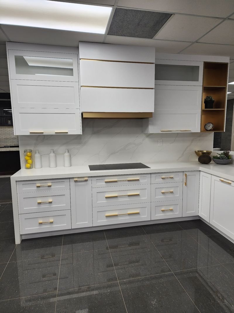 White kitchen with brass handles, a quartz backsplash and a slab range hood, renovated by Elm Kitchen