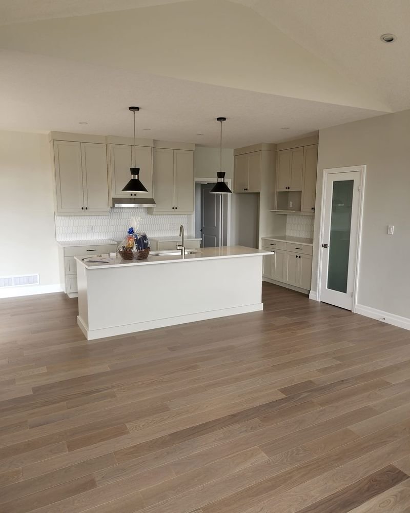 Open-concept white kitchen with an island and pendant lights, renovated by Elm Kitchen