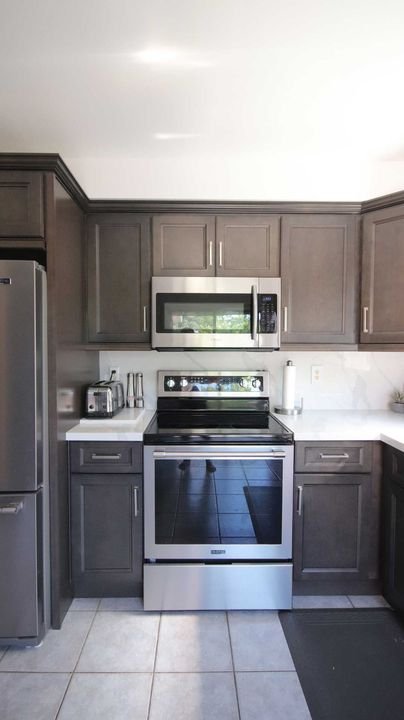 Range wall with an over-the-range microwave, London Grey cabinets by Canada Kitchens