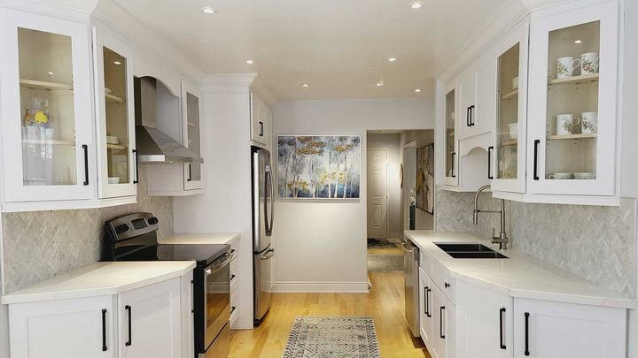Galley kitchen with glass-front uppers, Shaker White cabinets by Canada Kitchens